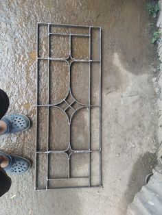 a person standing next to a metal grate on the ground with their feet up