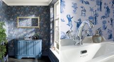 the bathroom is decorated with blue and white wallpaper, while the bathtub has been painted