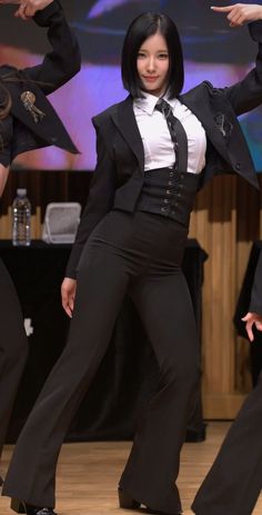 a woman in a black suit and white shirt is dancing