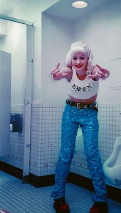 a woman standing in a bathroom with her hands up and wearing blue sequin pants