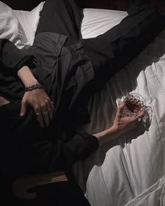 a woman laying on top of a bed holding a wine glass in her right hand