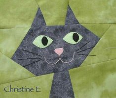 a close up of a cat made out of fabric on a piece of green paper