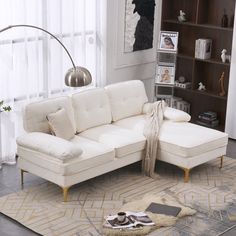 a white couch sitting on top of a rug in a living room next to a book shelf