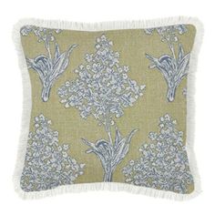 a green and white pillow with blue flowers on the front, fringe trim around the edges