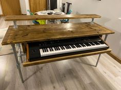 a wooden table topped with a keyboard and musical instrument on top of a hard wood floor