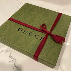 a gucci box with a red ribbon tied around it on a marble countertop