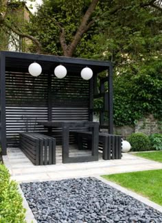 an outdoor seating area in the middle of a garden with rocks and gravel on the ground