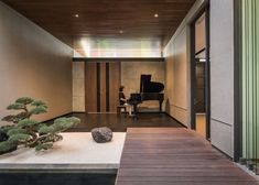 a person sitting at a piano in a room with wood flooring and walls on either side