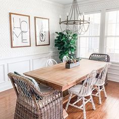 a dining room table with wicker chairs and a potted plant in the corner