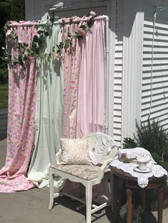 a chair sitting next to a window covered in pink and white curtains with flowers on them