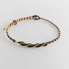 a black and gold rope bracelet on a white surface