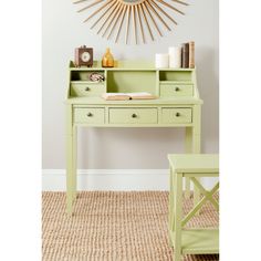 a green desk and chair in front of a wall with a sunburst above it