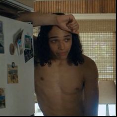 a shirtless young man is standing in front of a refrigerator with his hand on his head