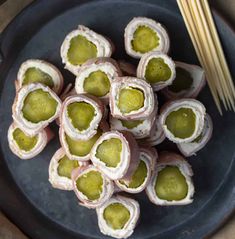 there are many rolls on the plate with some green stuff in them and chopsticks next to it