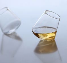 two glasses filled with liquid sitting on top of a white table next to each other