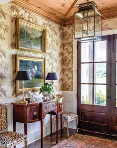 a living room with a chair, table and paintings on the wall next to an open door