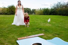 a woman and child are playing cornhole game in the grass with an adult nearby