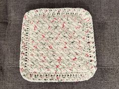 a white crocheted dishcloth with red and green designs