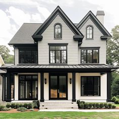 a large white house with black trim and lots of windows on the front porch,