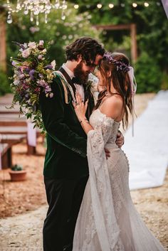 a bride and groom kissing in front of an outdoor ceremony arch with lights strung from the ceiling