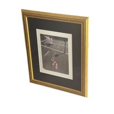 a black and gold framed photograph with pink shoes on the ground