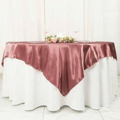 the table is covered with pink and white cloths, along with two wine glasses