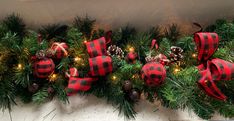 christmas garland with red and black plaid bows, pine cones and lights on the mantle