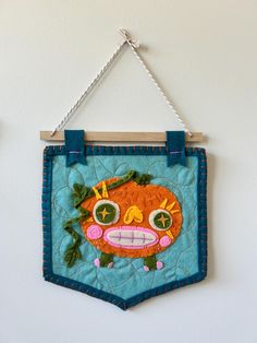 a wall hanging with an orange face on it