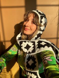 a woman wearing a black and white crocheted coat with hood on her head