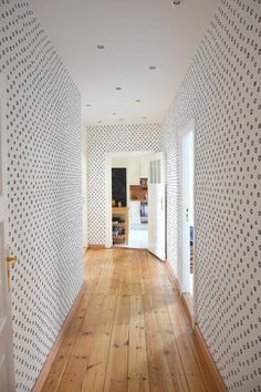 an empty room with wooden floors and white wallpaper on the walls is seen from another room