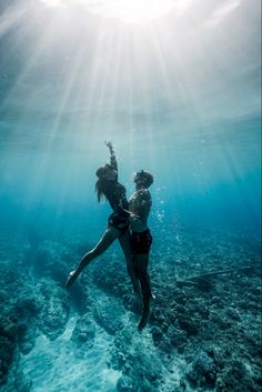 two people are swimming in the ocean with their backs to each other and arms outstretched