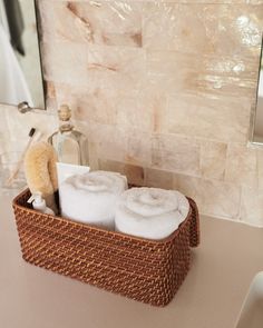 two rolls of toilet paper sitting in a basket on a bathroom counter next to a mirror