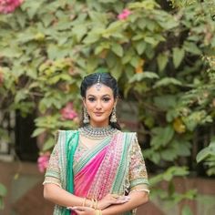 a woman in a pink and green sari posing for the camera with her hands on her hips