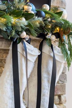 two stockings decorated with christmas ornaments and greenery are hanging on the fireplace mantel