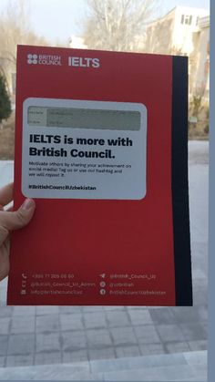 a person holding up a red book with the text ielts is more with british council