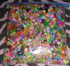 a bag filled with lots of different types of beads and other colorful items on a zebra print surface