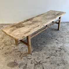 an old wooden bench sitting on top of a carpeted floor next to a wall