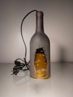 a bottle with a ship in it sitting on a table next to a charger