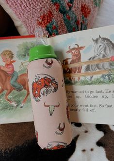 a pink and green water bottle sitting next to a book