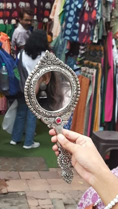 a person holding up a mirror in front of a store