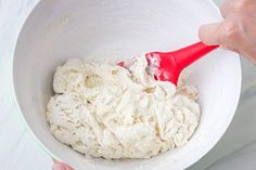 a person mixing food in a bowl with a red spatula