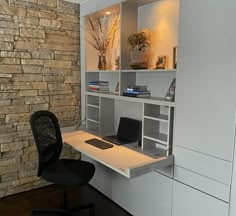 a computer desk with a laptop on it in front of a stone wall and shelves