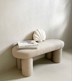 a white bench with a book on top of it and a seashell sitting on the back