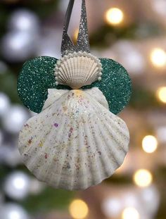 a christmas ornament hanging from the side of a tree with lights in the background