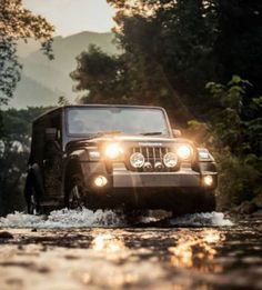 a jeep driving through water with the headlights on