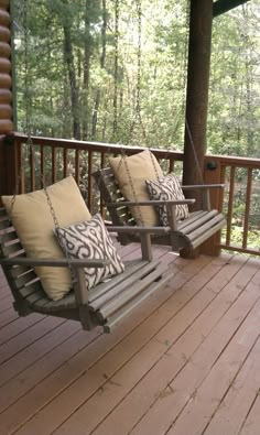 two chairs sitting on a porch with pillows hanging from the front and back of them