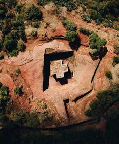 an aerial view of a rock structure in the middle of some trees and dirt ground