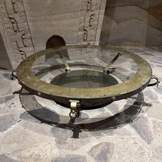 a round glass table with metal legs on stone floor