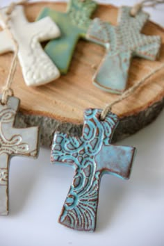 three ceramic crosses sitting on top of a piece of wood next to a slice of tree