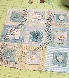 there is a crocheted square with buttons on the floor next to a sewing machine